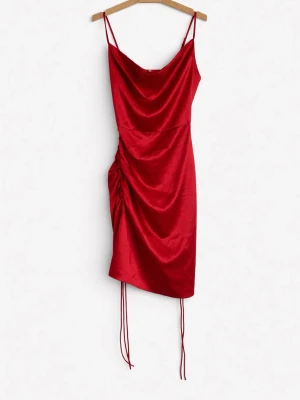 Röd satin klänning med snörning - Snygg röd kortklänning i satin med tunna axelband och draperad framsida. Klänningen har snörning i sidan för justerbar passform och en asymmetrisk nederkant. Perfekt för dig som vill sticka ut med en trendig look.