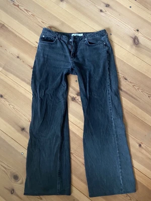 Svarta raka jeans från NA-KD - Säljer ett par svarta jeans från NA-KD i rak modell med låg midja. Jeansen har klassisk femficksdesign, dragkedjegylf och knapp framtill. Perfekta till en avslappnad och trendig look.