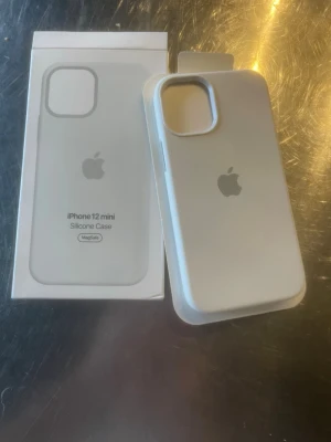 Vitt silikonskal Apple iPhone 12 mini - Snyggt vitt silikonskal från Apple till iPhone 12 mini. Skalet har en stilren design med Apple-loggan på baksidan och är kompatibelt med MagSafe. Tillverkat i mjukt silikon som ger bra grepp och skydd för mobilen.