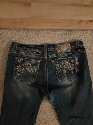 Miss me jeans - Säljer dessa bootcut jeans ifrån Miss Me med fina detaljer. Dem är slitna på insidan av låren efter användning(syns på bilderna) men annars är dem jättefina. Har inte tid eller material för att fixa det. Storlek 32, de är väldigt stretchiga så kan nog passa allt från L/XL- XXL. Priset är inte hugget i sten. Skriv om frågor uppstår☺️