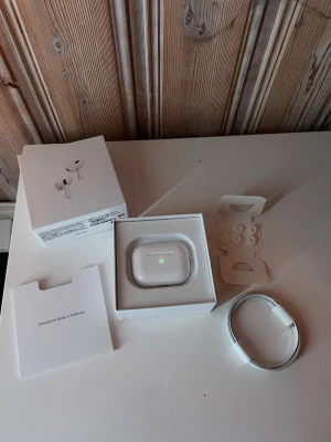 Apple AirPods Pro med laddningsetui - Säljer ett par vita Apple AirPods Pro med trådlöst laddningsetui. Hörlurarna har silikonproppar i olika storlekar, brusreducering och levereras med originalkartong, laddningskabel och tillbehör. Snygg och stilren design i blank plast.