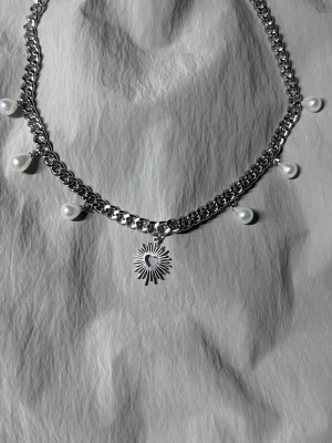 Statement Silver Pearl & Heart Necklace - Ett handgjort, modernt halsband som kombinerar lyster från pärlor med en skulptural hjärtdetalj. 40 cm kedja, kan förlängas vid behov. Tillverkat i rostfritt stål. Designat för att sticka ut.