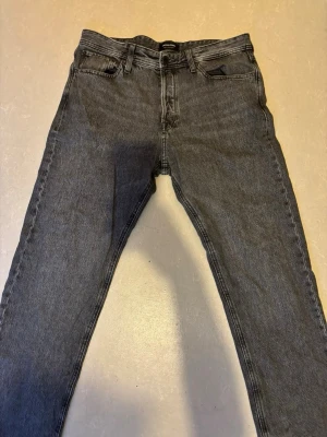 Svarta relaxed jeans från Jack & Jones - Säljer ett par svarta relaxed fit jeans från RELAXED/CHRIS i storlek 32/34. Jeansen har klassisk femficksdesign, raka ben och är tillverkade i ett slitstarkt denimtyg. Perfekta för en chill och avslappnad stil.