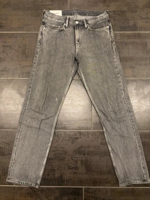 Grå relaxed fit jeans från H&M - Snygga grå jeans från H&M med relaxed fit och raka ben. Klassisk femficksmodell med knappgylf och slitstark denim. Perfekta för en avslappnad och trendig look. Storlek 31/32