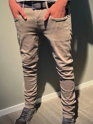Beige slim fit jeans med stretch - Snygga beige slim fit jeans med stretch. Jeansen har klassiska fem fickor, smal passform och är tillverkade i ett mjukt bomullsmaterial med lite elastan för extra komfort. Perfekta för en avslappnad och trendig look.