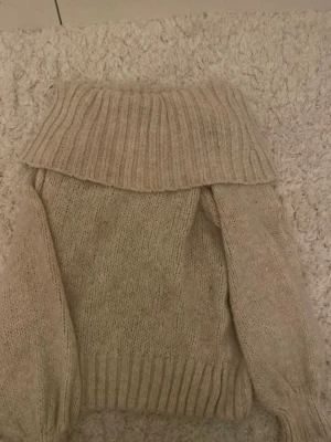 Beige stickad off-shoulder tröja Gina Tricot - Säljer en beige stickad off-shoulder tröja från Gina Tricot. Tröjan har ribbstickat off-shoulder och långa ärmar. Perfekt för kalla dagar och riktigt mysig att bära. Materialet är mjukt och ger en avslappnad look.