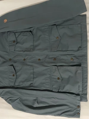 Field jacka från fjällräven - Snygg field jacket från fjällräven. Toppen skick, inga defekter. Varsamt använd ett fåtal gånger. Köpt på naturkompaniet, nypris: 3499. Ganska stor i passformen