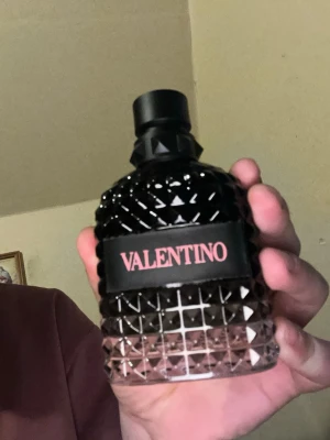 Valentino Uomo Born In Roma EdP 100ml - Valentino Uomo Born In Roma Eau de Parfum i 100 ml flaska. Flaskan är svart med nitar och har en lyxig, modern design. Förpackningen är svart med rosa text. En exklusiv herrdoft som sticker ut både i doft och utseende.använd en gång för att testa