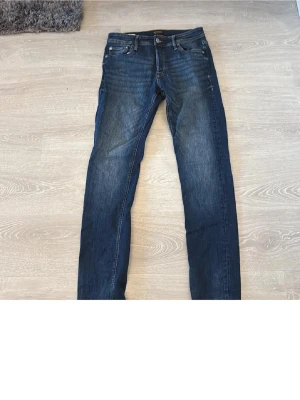 Blå slim fit jeans Jack & Jones - Säljer ett par blå slim fit jeans från Jack & Jones, modell Glenn. Jeansen har klassisk femficksdesign, normal midja och lätt slitna detaljer framtill. Tillverkade i denim med snygg tvätt och raka ben.
