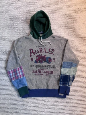 Patchwork hoodie från Polo Ralph Lauren - Unik hoodie från Polo Ralph Lauren med grå bas, grön huva och patchwork-detaljer på ärmarna i olika mönster och färger. Nyskick nästan aldrig använd. Nypris runt 3000. Skriv nid frågor!