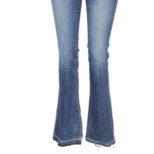 Blå Levi bootcut jeans med slitningar - Säljer ett par blå bootcut jeans med snygga slitningar och tvättade detaljer. Jeansen har klassisk femficksmodell, normal midja och dragkedja med knapp. Perfekta för en avslappnad och trendig look.