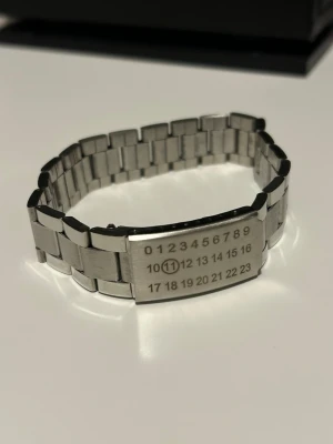 Maison Margiela armband  - Säljer ett silverfärgat Maison Margiela armband. Endast använd ett fåtal gånger och har inge märkvärdiga skador.