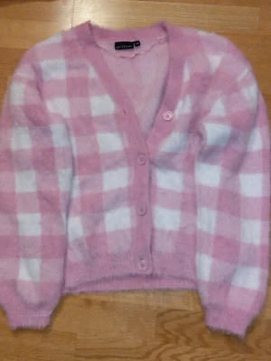 Rosa och vit rutig kofta - Mysig kofta i fluffigt material från XOXO friends. Köpt i Ullared. Storlek 170. Koftan är rosa och vit med rutigt mönster, har v-ringning och stängs med fyra matchande knappar framtill. Tjock, mysig och gullig. Oversized. Perfekt för dig som gillar söta och bekväma plagg. Använd 1-2 gånger. 