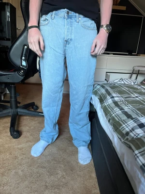 Ljusblå raka jeans - Säljer ett par ljusblå jeans med rak passform och klassiska fem fickor. Jeansen har normal midja och är tillverkade i denim. Perfekta för dig som gillar en avslappnad och tidlös stil. Jeans från Jack & Jones i modellen Loose Eddie, storlek 30/32. Använda ett fåtal gånger.