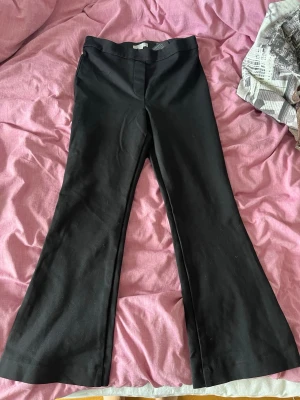 Svarta kostymbyxor med bootcut - Snygga svarta kostymbyxor med utsvängda ben och klassisk passform. Storlek S. Har ingen dragkedja utan är strechigt material. 