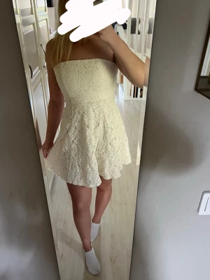 Vit spetsklänning - Säljer en söt kortklänning med vacker spets och utsvängd kjol. Formar sig fint efter kroppen och går in vid midjan. Klänningen har inga band och dragkedja baktill. Passar perfekt till student eller sommaren.    Märke: se bild