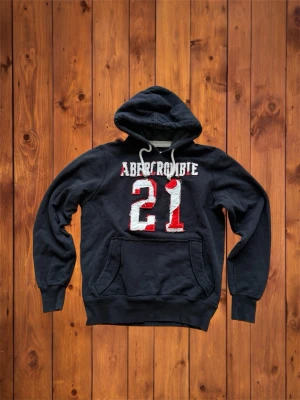 Vintage Abercrombie&Fitch Hoodie (sällsynt)  - Säljer denna vintage hoodien från Abercrombie&Fitch, den har sjukt snygg design på framsidan med feta detaljer och är väldigt sällsynt. Den är i väldigt bra skick och storleken är M. Vid funderingar eller annat kom dm, se måtten nedan.  B=66cm A=55cm