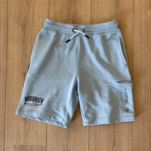 🩵Ljusblå shorts från Hoodrich🩵 - Säljer ett par ljusblå shorts från Hoodrich med snörning i midjan och praktiska fickor. Shortsens material är mjukt och bekvämt, perfekt för chill dagar. Hoodrich-loggan är broderad på ena benet och det finns en extra ficka med dragkedja på sidan. Passar dig som är 165-150 cm i längd.