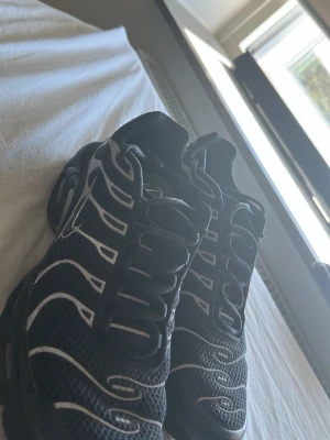 Nike Air Max Plus svarta sneakers - Nike Air Max Plus sneakers i svart mesh med reflekterande linjer. Skorna har den ikoniska TN-loggan på sidan och en chunky sula med synliga Air-enheter. Snygg, sportig design som sticker ut och passar perfekt till streetwear. Köpta nya 2600kr