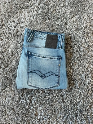 Ljusblå jeans från Replay - Säljer ett par ljusblå jeans från Replay med klassisk femficksdesign och snyggt broderad bakficka. Jeansen har raka ben och är gjorda i bomull med lite stretch för skön passform. Perfekt för dig som gillar en avslappnad och trendig look. W31 L34