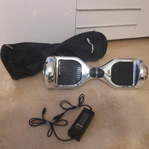 Silver hoverboard med laddare och väska - Säljer en cool och snabb hoverboard i spegelblankt silver med svarta fotplattor. Medföljer laddare och en svart bärväska från Hoverboard. Perfekt för att ta sig fram snabbt och smidigt. Laddaren har svart kabel och hoverboarden har rundade former. Något sliten i färgen, men det gör ju inget.. 5995 kr i nypriset, se länken för samma produkt och pris. Används på eget ansvar.. 😅 Säljer den för att jag inte har balansen kvar för sånt här... 😂✌️  https://matplatsen.net/wheelboard-rabattkod/    
