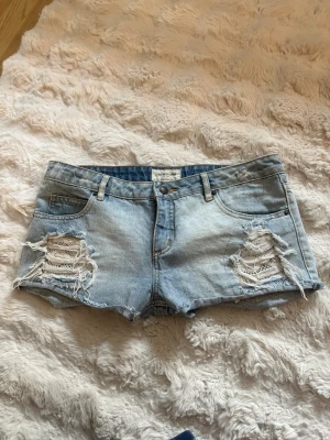 Ljusa jeansshorts med slitningar - Säljer ett par ljusblå jeansshorts med slitna detaljer i storlek S! Super snygga detaljerar och köpta här på plick men tyvärr för stora, säljer därför om dem nu💓