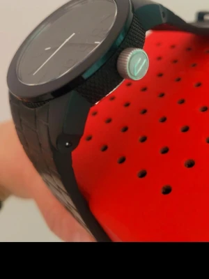 Svart klocka från Diesel med röda Box  - Cool svart klocka från Diesel med mattsvart boett och armband i syntetmaterial. Urtavlan har mörka siffror och markeringar som verkligen sticker ut. Perfekt för dig som vill ha en stilren accessoar med attityd.