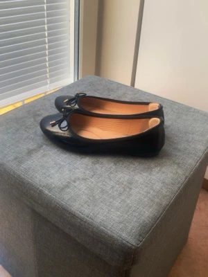 svarta ballerina skor med rosett - svarta ballerina skor med rosett. Lite färg defekter på sulan men inget som påverkar hur det ser ut när man har på sig de.  De har skydd på hälen så att man inte får skoskav.