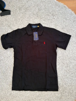 Ralph lauren svart pike - Mycket fin Ralph Lauren piké i svart färg. Storlek M. Helt oanvänd