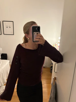 Vinröd stickad tröja med vida ärmar - Mysig vinröd stickad tröja med vida ärmar. Tröjan har en enkel design utan synliga mönster och är perfekt för att hålla värmen under kyliga dagar. Materialet ser ut att vara mjukt och fluffigt. skriv för fler bilder eller diskutera pris💕