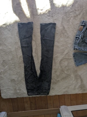 Grå bootcut jeans med låg midja - Säljer ett par grå bootcut jeans med låg midja och klassisk femficksdesign. Jeansen har en lätt tvättad look och är tillverkade i denim med stretch för extra komfort. Perfekta för dig som gillar en avslappnad men trendig stil.