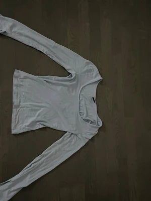 Ljusblå långärmad topp Gina Tricot - Ljusblå långärmad topp från Gina Tricot med rundad, något djupare halsringning. Tillverkad i mjukt material som känns skönt mot huden. Perfekt att styla med jeans eller kjol för en enkel och snygg look. Delat i slutat av ärmarna
