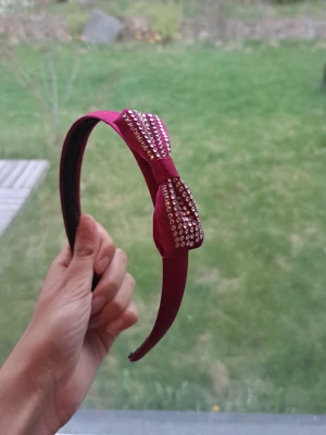  Diadem med rosett & strass Barbie popstar 2000s - Snyggt unikt Violet, plum diadem med en dekorativ rosett täckt av glittrande strass. Diademet är klätt i ett sammetsliknande tyg och har en klassisk bågform. Perfekt accessoar för att lyfta din look med lite extra bling. 2000s vintage barbie popstar