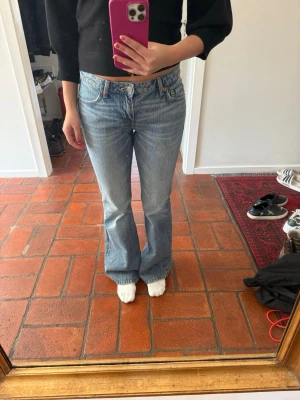 Ljusblå bootcut jeans från Levi's - Säljer ett par ljusblå bootcut jeans från Levi's med klassisk femficksdesign och normal midja. Jeansen har en lätt tvättad look och subtila slitningar, tillverkade i denim med en skön passform. Perfekta för dig som gillar retrostil och vill ha ett par snygga jeans i garderoben.
