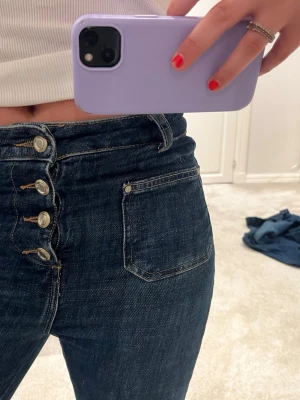 Mörkblå bootcut jeans med knappar - Snygga mörkblå bootcut jeans med hög midja och fyra silverfärgade knappar framtill. Älskar dessa jeans🌷. 