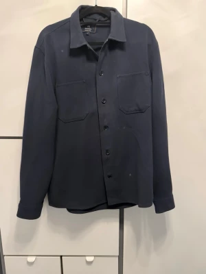 Mörkblå overshirt  - Säljer en Matinique overshirt i fint skick.  Stilren och modern skjortjacka som funkar perfekt som ett lager över t-shirt eller skjorta. Lätt att matcha och ger en snygg, avslappnad men ändå uppklädd look.  Perfekt för både vardag och lite finare tillfällen. Mjuk och bekväm kvalitet med klassisk passform som sitter bra. Sparsamt använd och väl omhändertagen. 