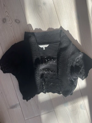 Svart kortärmad  bolero - Svart stickad bolero från Clockhouse med korta ärmar och öppen front. köpt på karlaplan loppisen men är knappt använd! storlek M men passar xs-m❣️❣️
