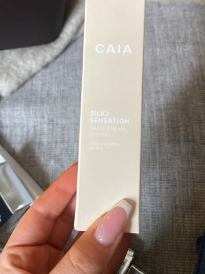 CAIA Silky Sensation Handkräm - Handkräm från CAIA i doften warm amber. Innehåller mangokärnesmör och aloe vera för extra återfuktning. Förpackningen är ljusbeige och stilren, perfekt att ha i väskan eller på skrivbordet.