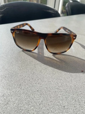 Solglasögon Ray-Ban - Snygga solglasögon från Ray-Ban med brunmelerad båge och bruna tonade glas. Klassisk modell med Ray-Ban-logga på sidan och framtill. Perfekt accessoar för att lyfta din stil under soliga dagar. Kontakta vid frågor!