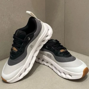 ON skor - Snygga On  sneakers i grått och vitt med svarta detaljer och brun sula framtill. Skorna har en chunky, ventilerad sula och ovandel i mesh och syntet. Perfekta för en sportig och modern look med cool design och bekväm passform.