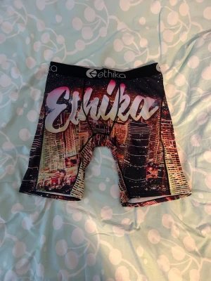 Färgglada kalsonger från Ethika - Säljer ett par färgglada kalsonger från Ethika med stadsmotiv och stor logga framtill. Kalsongerna har svart resår med Ethika-tryck och är tillverkade i ett stretchigt material som sitter skönt. Perfekta för dig som gillar unika och snygga underkläder.