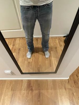 Ljusblå raka jeans från jacka and jonses - Säljer ett par ljusblå jeans från jack and jones med rak passform och slitna detaljer vid benslut. Jeansen har klassisk femficksmodell, dragkedjegylf och är tillverkade i denim. Perfekta för en avslappnad och trendig look. Mfg originals
