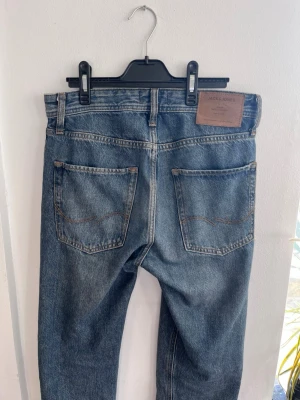 Blå jeans från Jack & Jones - 28/32   Klassiska blå jeansbyxor från Jack & Jones med rak straight passform och normal midja. Jeansen har fyra fickor, snygg tvättad denim och läderpatch med logga bak, hör av er om frågor 