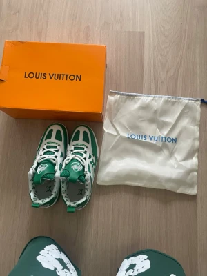 Gröna Louis Vuitton sneakers - Säljer ett par gröna och vita Louis Vuitton sneakers med ikoniska monogramdetaljer och blommor på sidan. Skorna har en chunky sula, vita skosnören och är tillverkade i en mix av läder och textil. Kommer med originalkartong och dustbag.
