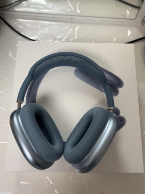 Blå Apple AirPods Max 2 hörlurar - Snygga over-ear hörlurar från Apple i blått med mjuka, vita öronkuddar och metalliska kåpor. Bygeln har mesh-tyg för extra komfort och designen är riktigt stilren och modern. Perfekta för dig som vill ha grymt ljud och cool look.