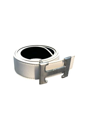 Vitt skärp med silverfärgat H-spänne - Snyggt vitt skärp med ett ikoniskt H-format spänne i silverfärg. Bältet är gjort i skinn och har en stilren, klassisk design som passar till många olika outfits. Perfekt accessoar för dig som gillar exklusiva detaljer.