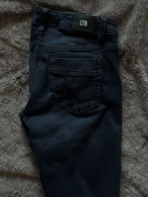 Mörkblå jeans från LTB - Säljer ett par mörkblå jeans från LTB med klassisk femficksdesign och raka ben. Jeansen har en snygg tvätt och är tillverkade i ett mjukt denimtyg som sitter skönt. Perfekta för dig som gillar stilrena och tidlösa jeans.