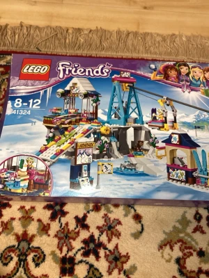 LEGO Friends Skidbacke 41324 - Säljer ett LEGO Friends set, Skidbacke 41324, med vintertema. Setet innehåller lift, skidbacke, snögrotta och flera minifigurer. Färgerna är mestadels blå, vit och lila. Perfekt för dig som gillar att bygga och skapa egna vinteräventyr.