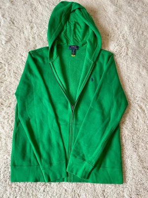 Grön hoodie från Polo Ralph Lauren - Riktigt snygg grön zip hoodie från Ralph Lauren. Barnstorlek XL vilket funkar som XS/S. Så gott som ny och knappt använd! Kontakta vid funderingar!🙌🤝☺️