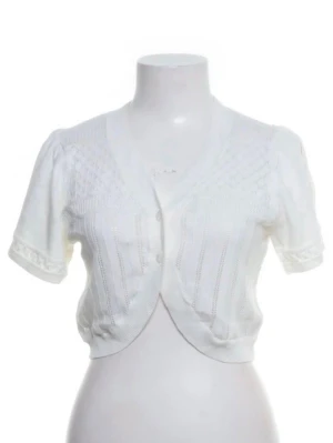 Vit kortärmad bolero - Söt vit stickad bolero med korta ärmar och knäppning framtill. Den har ett diskret mönster och är perfekt att slänga över en klänning eller topp.